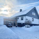 Wohnhaus mit Schneebedecktem Dach und Carport. Ein Auto steht unter dem Carport.