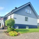 Ferienhaus mit blau-weißer Fassade, Vorgarten mit Blumen und Treppenhaus.