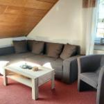 Wohnzimmer mit Sofa, Sessel und Holzdecke.