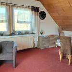 Wohn- und Essbereich mit Tisch, Stühlen, Fenstern und Holzdecke.