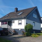 Haus mit blau-weißem Fassaden, Dach mit Dachfenstern und gepflasterter Vorplatz.