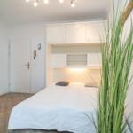 Schlafzimmer mit Bett, Schrank und Pflanze
