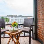 Terrasse mit zwei Stühlen, Tisch und Blumenstrauß. Blick auf Gebäude und Straße.