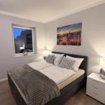 Schlafzimmer mit Doppelbett, Fenster und Wandbild.