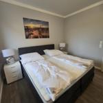 Schlafzimmer mit Doppelbett, zwei Nachttischen und Wandbild.