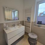 Badezimmer mit Waschbecken, Spiegel und Fenster