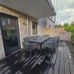 Terrasse mit Tisch und Stühlen, angrenzend an ein Haus mit Backsteinmauer.