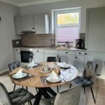 Runde Tisch mit Stühlen und Küchenbereich mit Fenster.