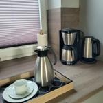 Kaffeemaschine, Wasserkocher und Thermoflasche auf Küchenarbeitsfläche.