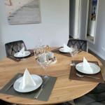 Runder Holztisch mit vier Stühlen und gedeckten Plätzen.