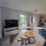 Wohnzimmer mit TV, Tisch, Sofa und Blick auf die Terrasse.