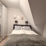 Schlafzimmer mit Dachschrägen, Bett, Nachttische und Spiegelschrank.