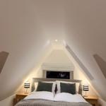 Schlafzimmer mit Doppelbett, zwei Nachttischen und schrägen Wänden.