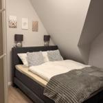 Schlafzimmer mit Doppelbett, zwei Nachttischen und drei Wandbildern.