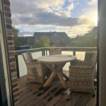 Terrasse mit Tisch und Stühlen, Blick auf Häuser und Bäume.