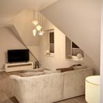 Wohnzimmer mit Sofa, Fernseher und schrägen Wänden.