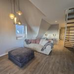 Wohnzimmer mit Sofa, Hocker und Treppe zur oberen Etage.