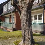 Rotes Backsteingebäude mit Balkon und grüner Rasenfläche.