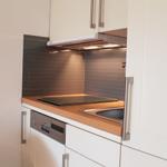 Küche mit Arbeitsplatte, Spüle und Dunstabzugshaube.