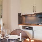 Küche mit Essbereich, weißen Schränken und Küchengeräten.