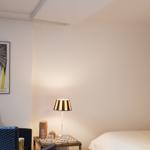 Schlafzimmer mit Bett, Nachttisch, Lampe und Wandbild.