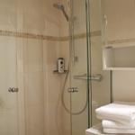 Dusche mit Glaswand, Handtuchstapel und Spiegelschrank