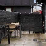 Terrace with table, chairs, and dark wooden walls. Tile floor and slatted fence visible.