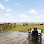 Terrace with table and chairs, view of beach and sea.