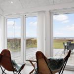 Living room with view of beach and terrace with garden furniture and telescope.