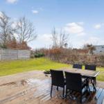 Terrasse mit Tisch und Stühlen, grüner Rasen und Zaun im Hintergrund.