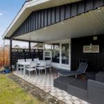 Terrasse mit Tisch, Stühlen und Liege. Schwarze Holzwände und Glasfront.
