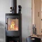 Holzofen mit brennendem Feuer und Holzkohlebehälter daneben.