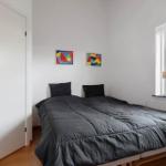 Schlafzimmer mit Bett, Fenster und zwei Bildern an der Wand.