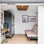 Raum mit Futon, Schreibtisch und Garderobe. Holzboden und weiße Wände.