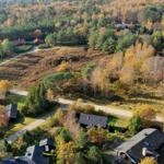 Luftaufnahme von Ferienhäusern in einem Waldgebiet mit Herbstlaub.