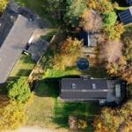 Luftbild von mehreren Häusern mit Dächern und einem runden Pool im Herbst.