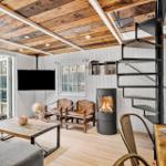 Wohnraum mit Kamin, TV und Treppe zur oberen Ebene.