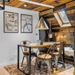 Essbereich mit Holztisch, Metallstühlen und Deckenfenster.