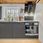 Küche mit dunklen Schränken, Herd und Fenster mit Blick auf Bäume.