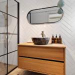 Bath with shower, sink, and mirror on herringbone wall