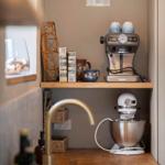 Kitchen area with coffee machine and stand mixer on wooden shelf.