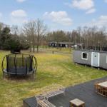 A gray holiday home with terrace, table, chairs, and trampoline on a green lawn.