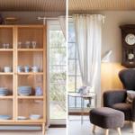 Wooden cabinet with dishes near window. Armchair with ottoman and wall clock.