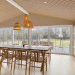 Dining room with wooden table, chairs, and large windows to the garden.