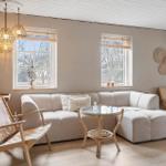 Living room with sofa, chairs, and table. Two windows, ceiling lights, and wall decor.