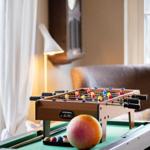 Foosball table on green pool table with balls and a fruit