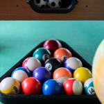 Pool table with balls in triangle and two soccer balls in compartment.