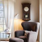 A room with a brown armchair, a side table, and a wall clock.
