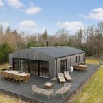 Modern wooden cabin with large terrace and garden.