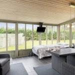 Sun terrace with sleeping area, seating group, and TV. View of garden and fence.